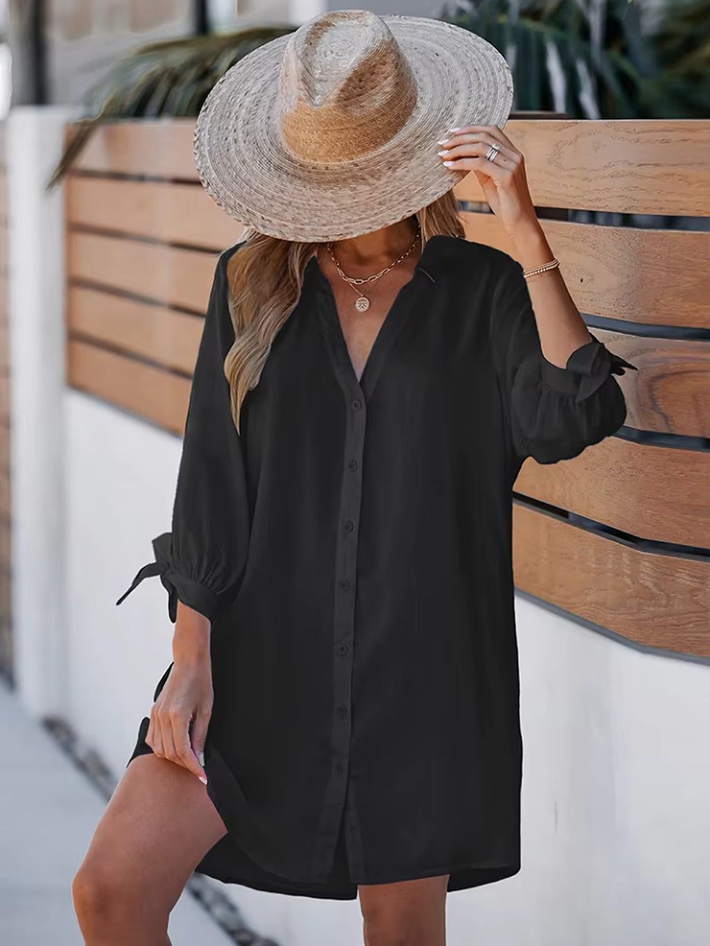 Woman wearing black button-up beach cover-up shirt over striped catch bikini with wide-brimmed straw hat