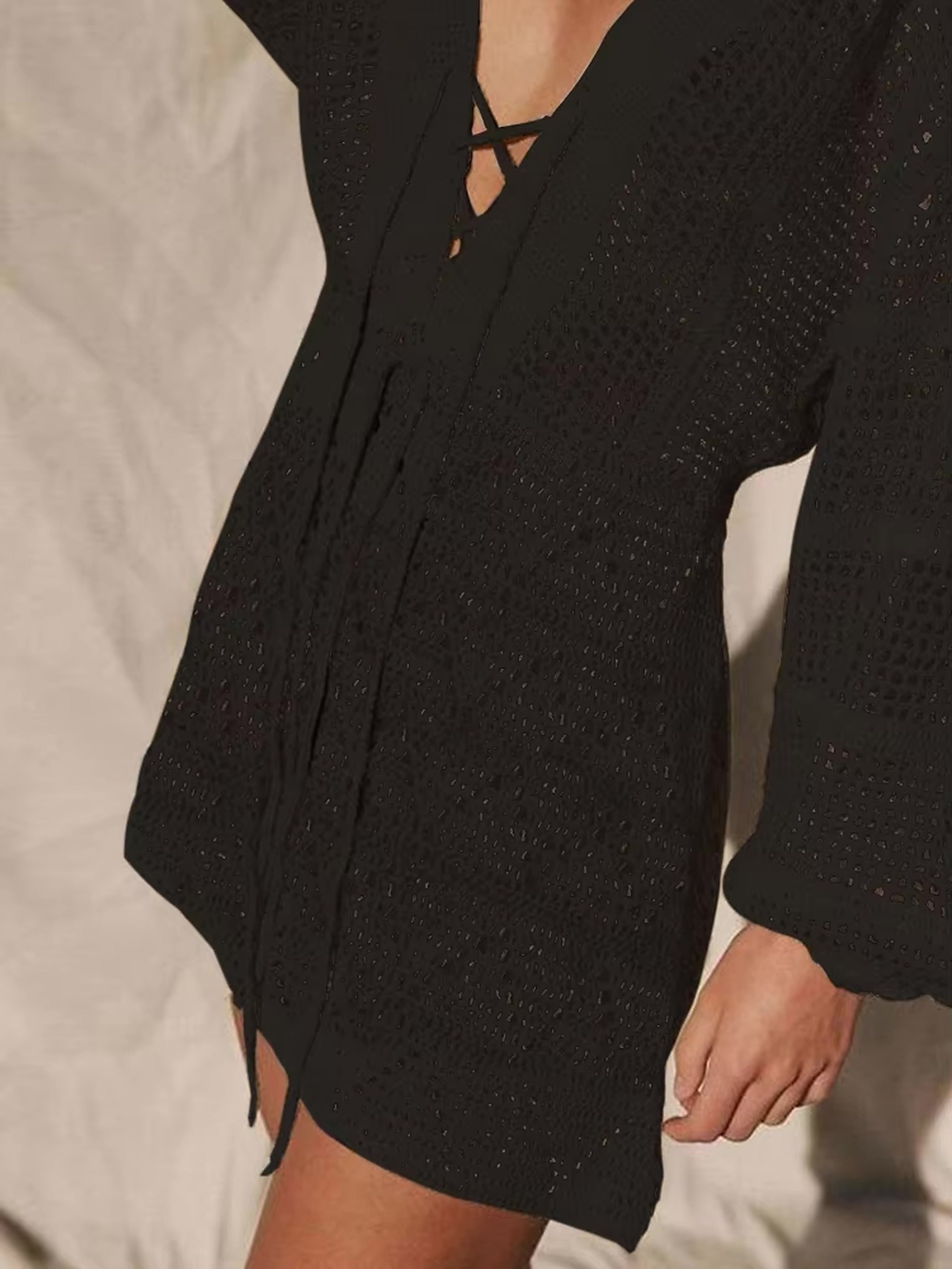 Black long-sleeve knit bikini cover-up with textured fabric and front tie closure detail.