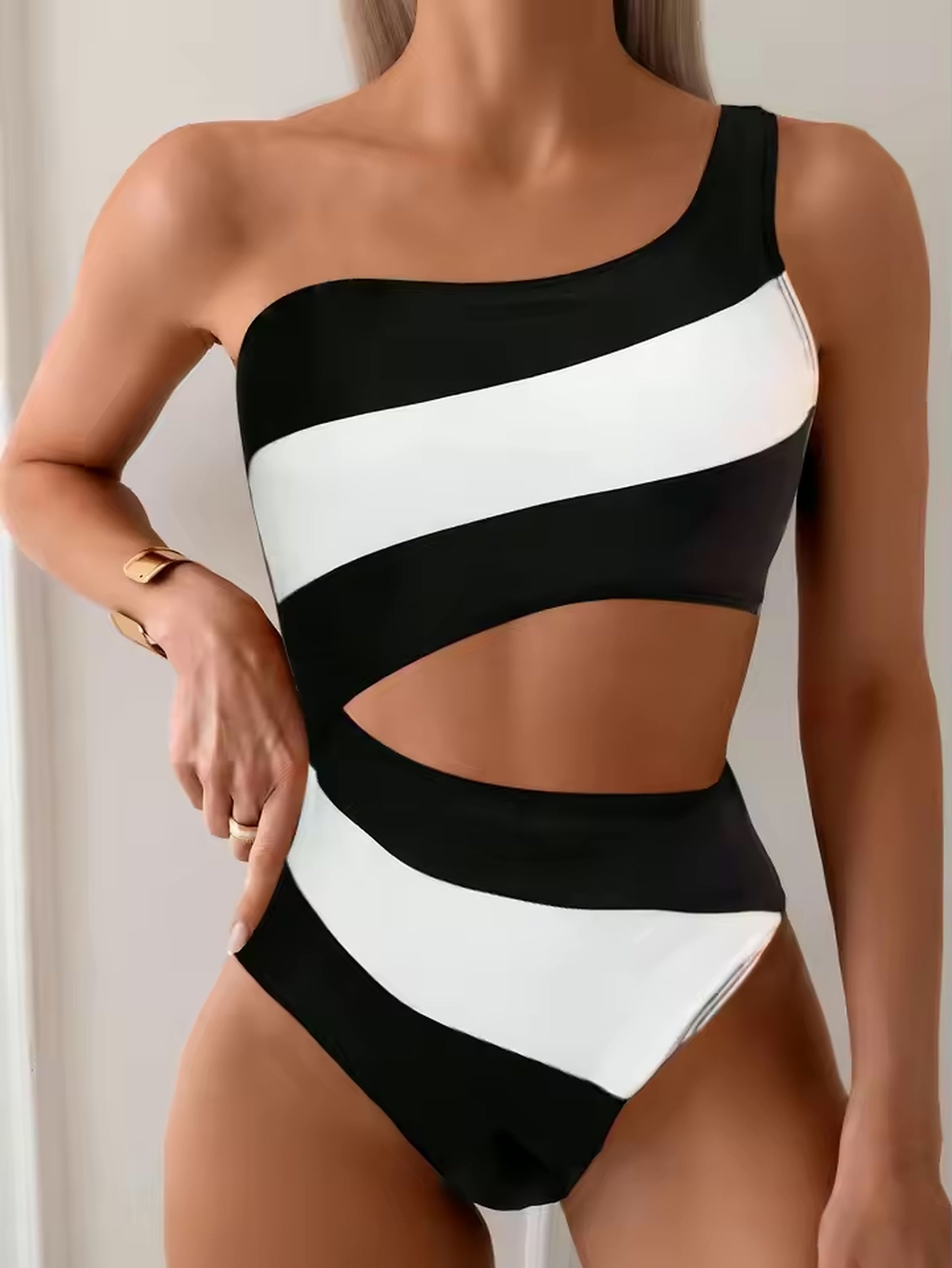 Woman wearing black and white striped one-piece swimsuit with asymmetrical neckline and cutout details