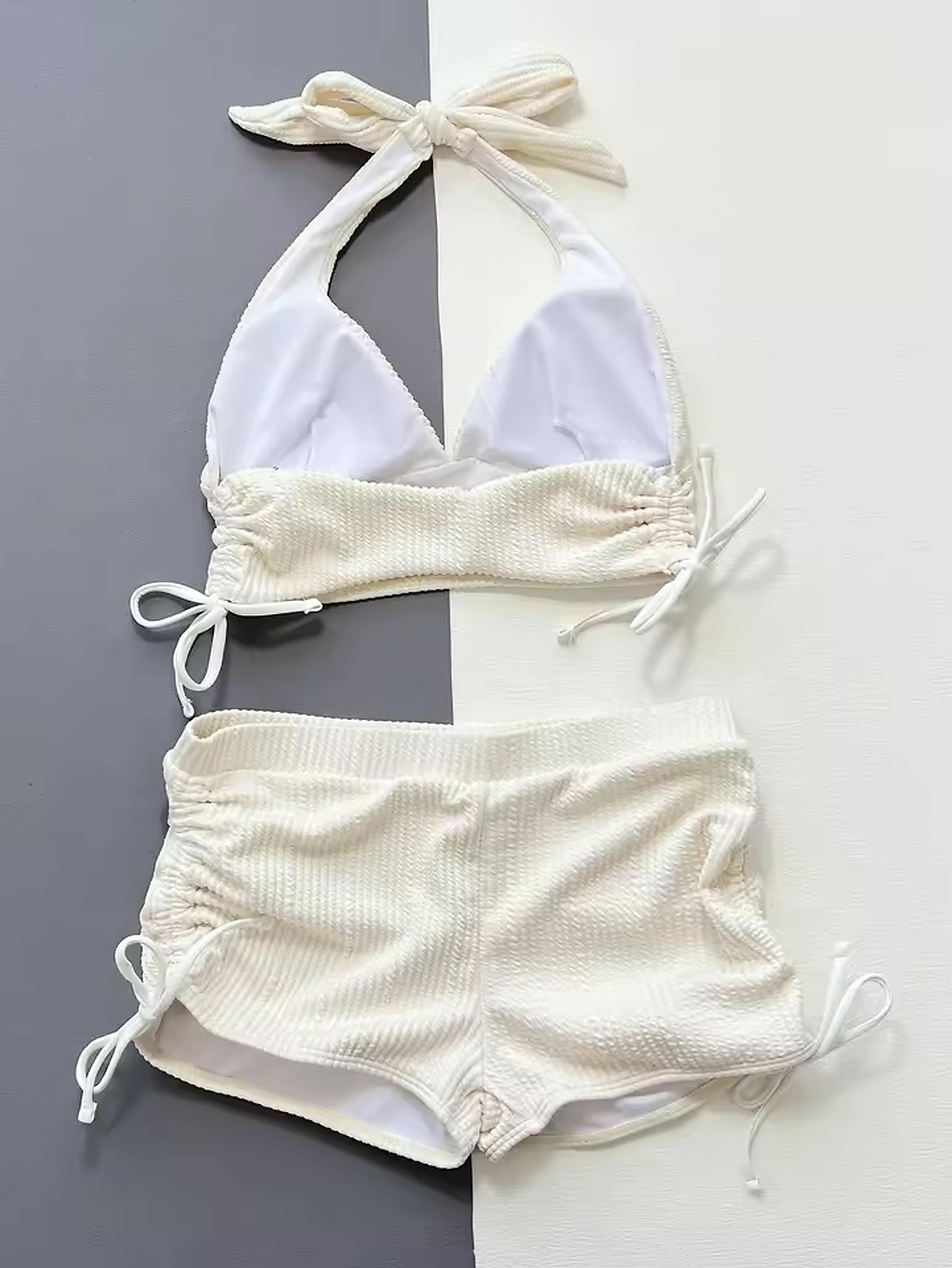 White textured bikini with halter neck top and ruched high-waist bottoms on two-tone background