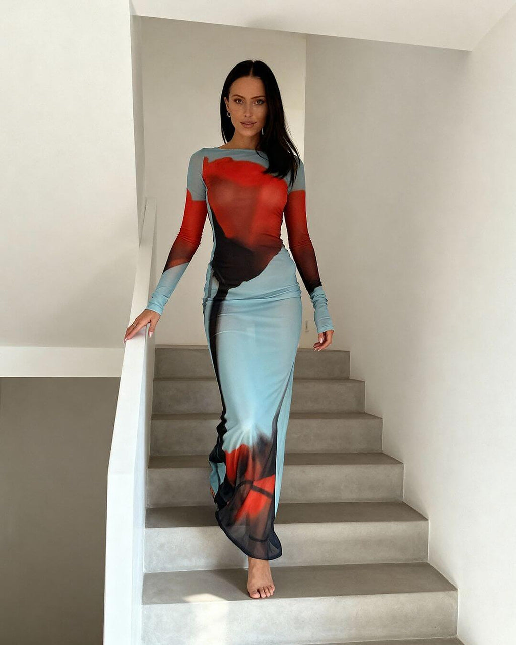 Woman wearing red, blue, and black Ocean Mirage bikini with long sleeves and matching skirt on stairs