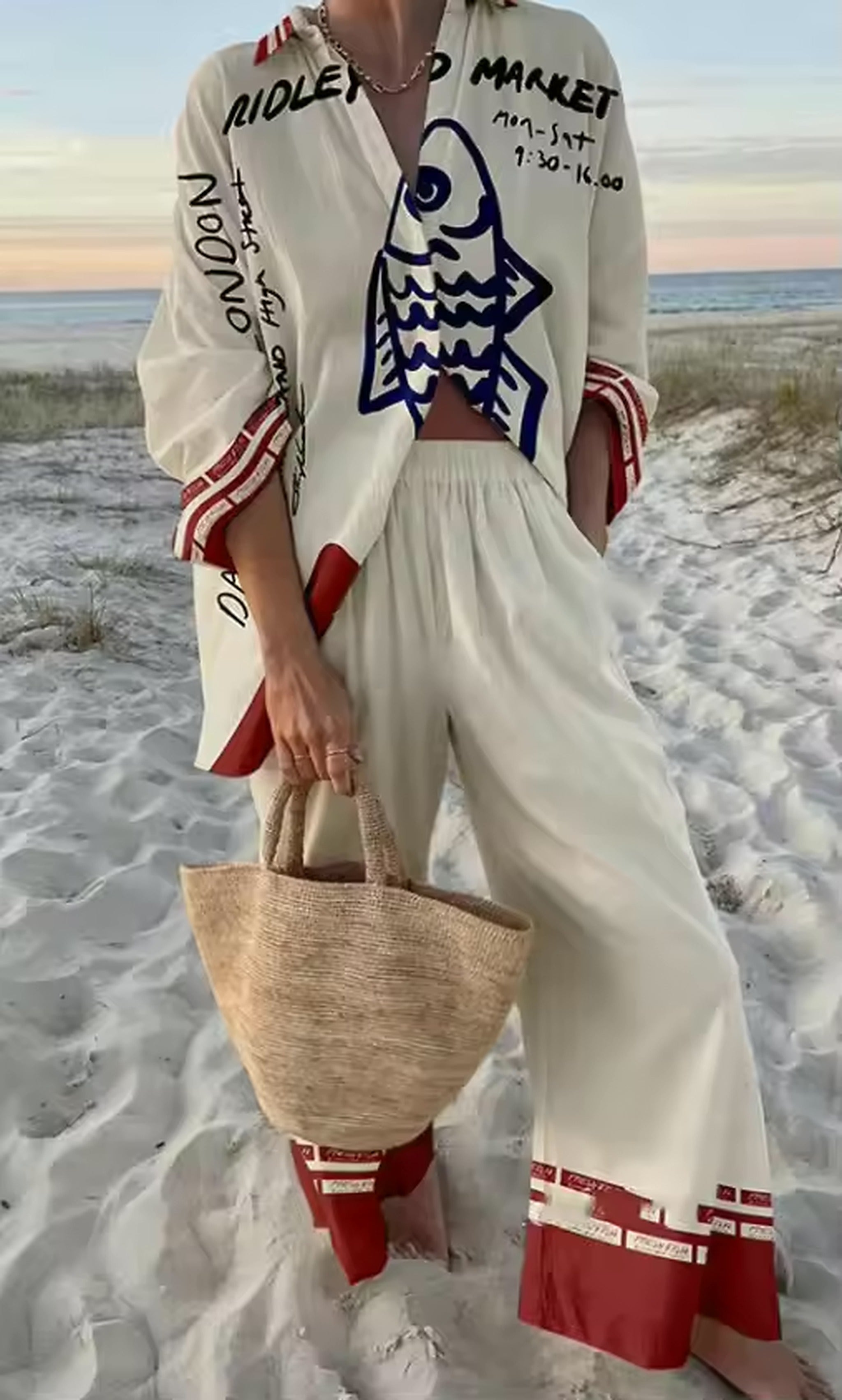 Woman wearing white Savanna Siren bikini with red and navy graphic print on beach at sunset