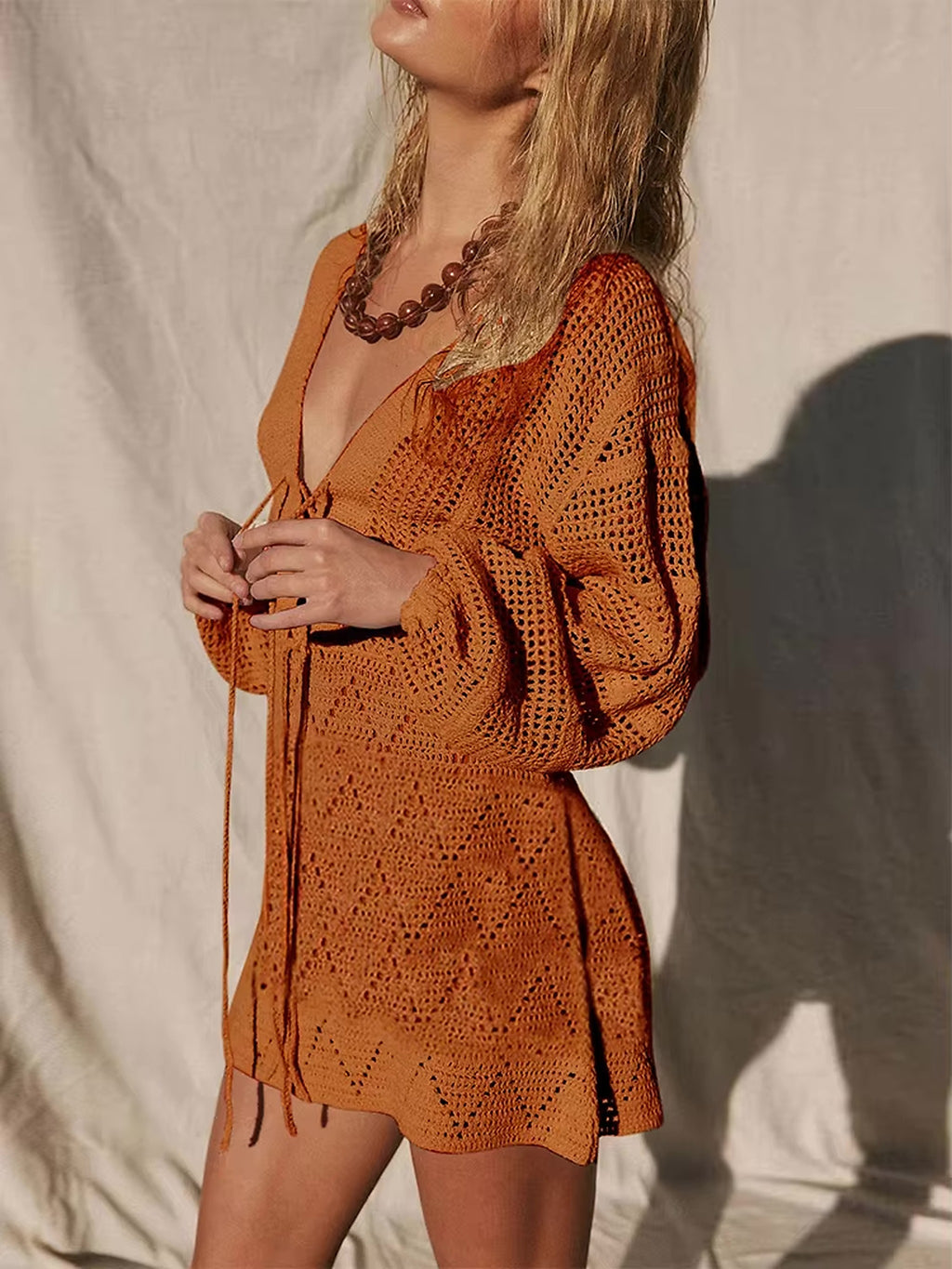 Woman wearing Golden Siesta orange crochet bikini cover-up dress with tie front and puffed sleeves