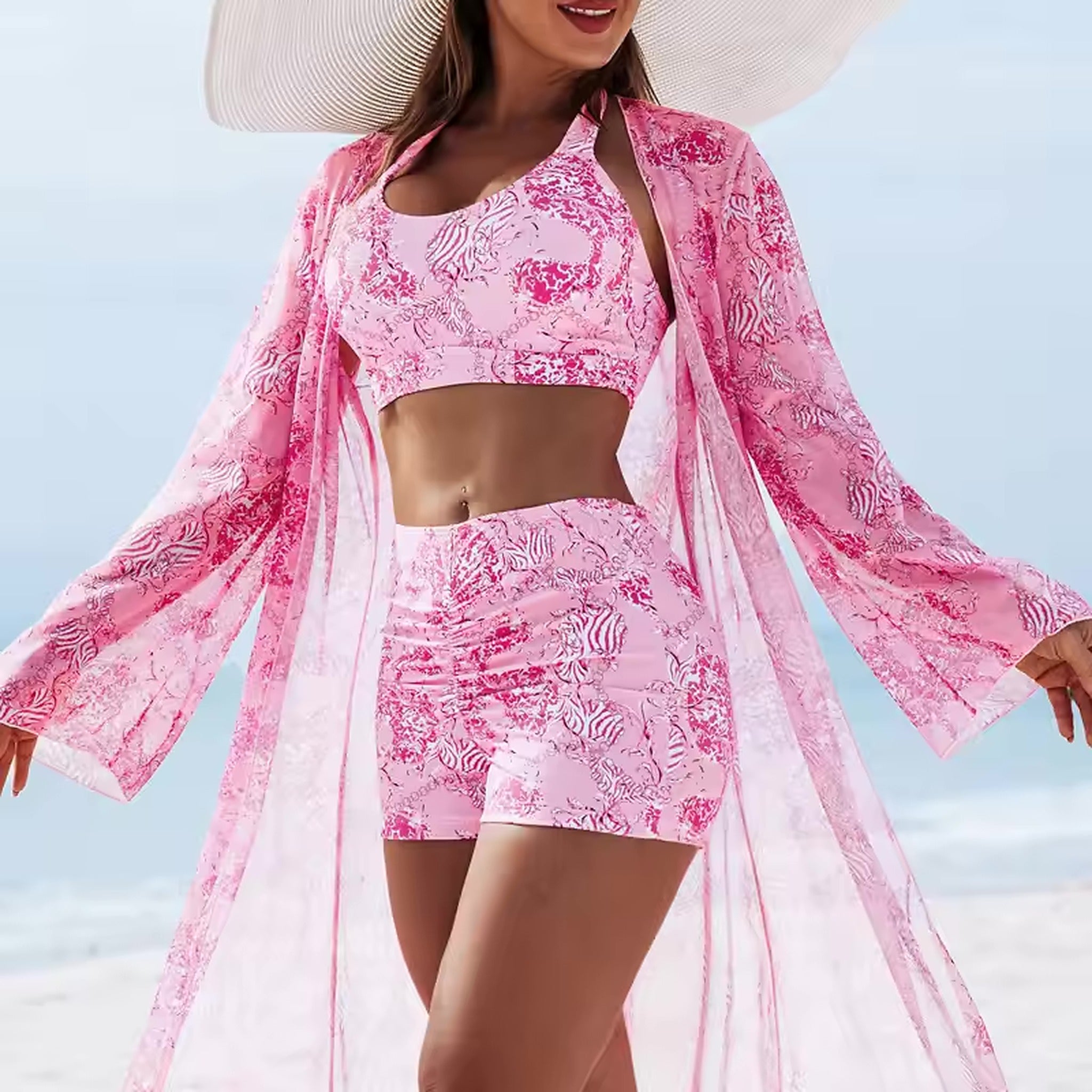 Pink patterned bikini with matching sheer cover-up worn on the beach with a wide-brimmed hat