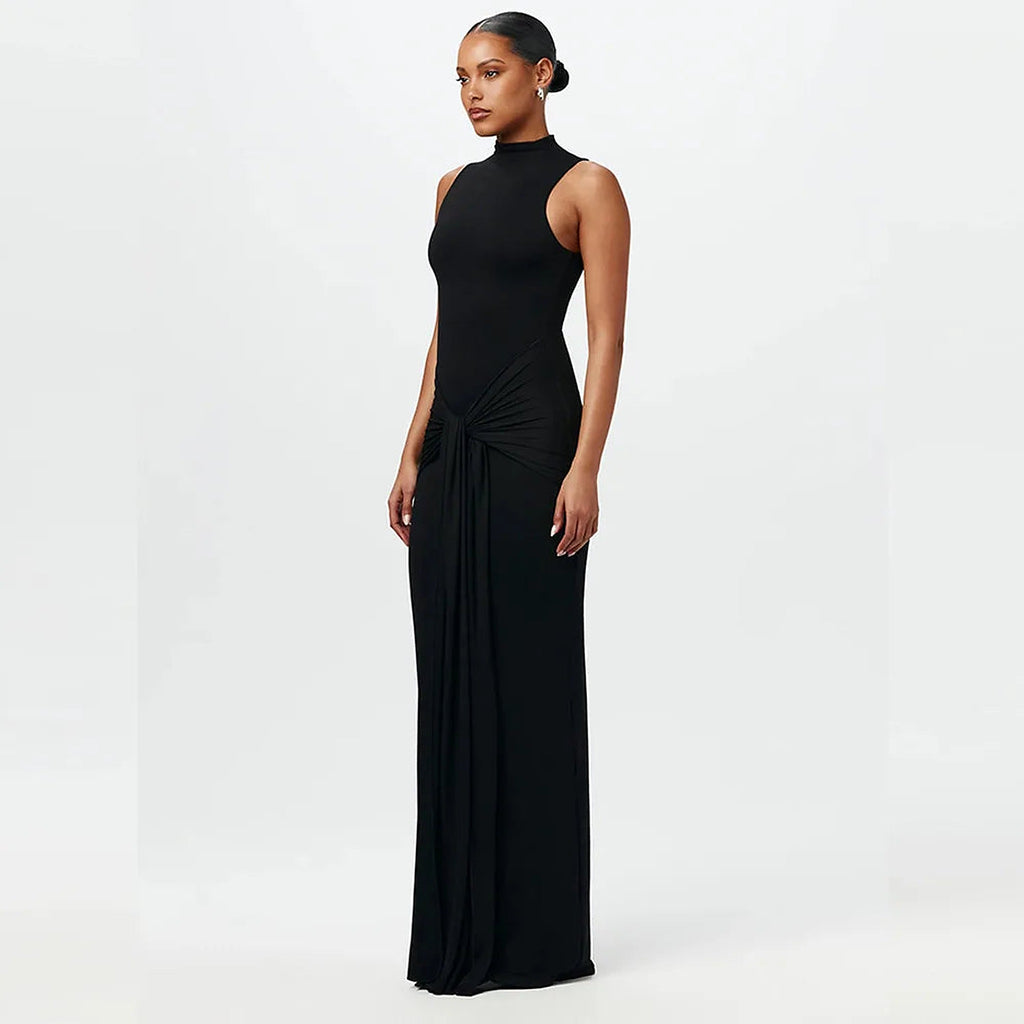 Woman wearing black sleeveless high-neck Maia bikini with draped side detail, full-length view against white background.